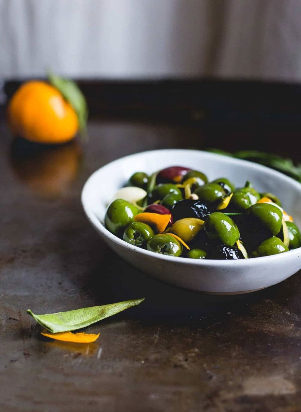 Bowl of mixed olives with herbs and citrus peels.